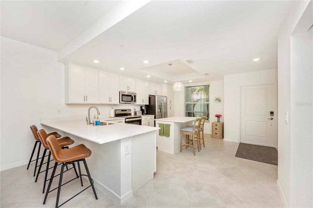 17500 Opal Sand Drive, Unit 101 Venice, FL 34293 - Photo 4 of 98 a kitchen with a dining table chairs and white cabinets
