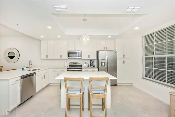 a kitchen that has a lot of white cabinets and stainless steel appliances