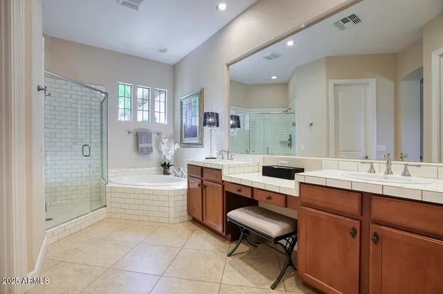 a bathroom with a sink double vanity granite tub shower and a mirror