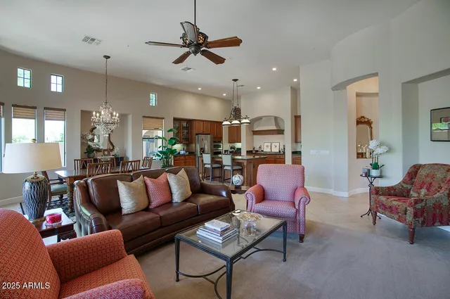 a living room with furniture kitchen view and a chandelier
