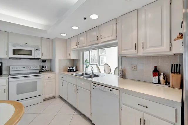 a kitchen with a sink dishwasher a stove and white cabinets