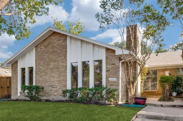 a view of a house with brick walls and a yard with potted plants