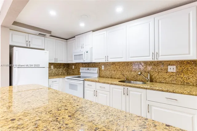 a kitchen with a sink cabinets and white appliances