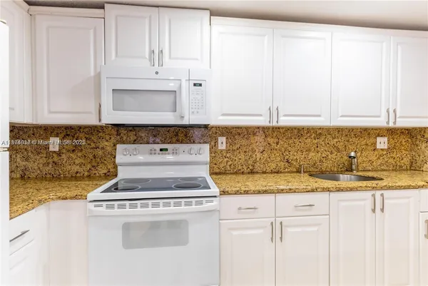 a kitchen with granite countertop white cabinets and white appliances