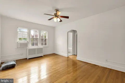 an empty room with wooden floor fan and windows