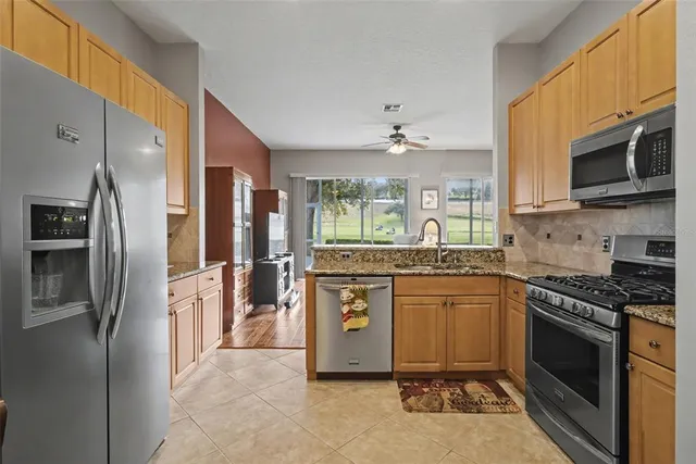 a kitchen with stainless steel appliances granite countertop a stove top oven a refrigerator and a sink