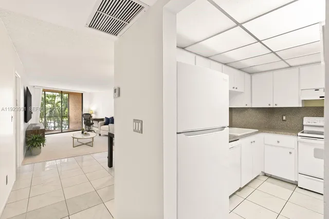 a kitchen with a refrigerator a stove top oven a sink and white walls