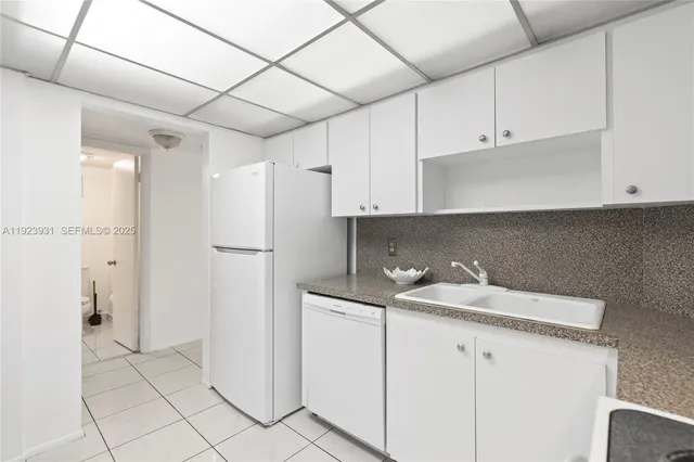 a kitchen with white cabinets and refrigerator
