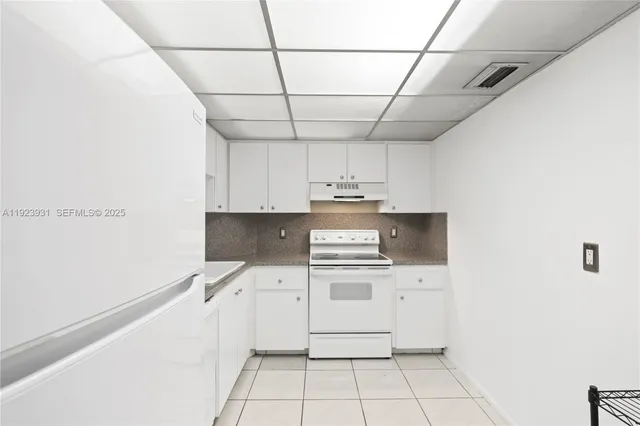 a kitchen with a stove a sink and white cabinets