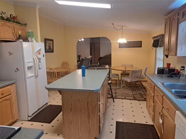 a kitchen with a sink a refrigerator and chairs