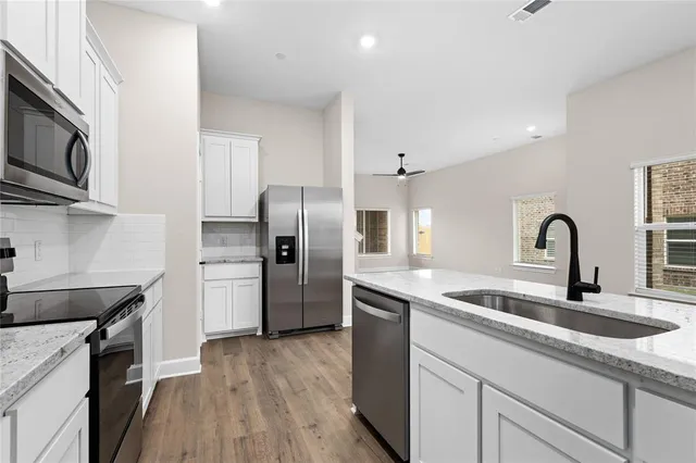 a kitchen with stainless steel appliances granite countertop a kitchen island hardwood floor sink and stove
