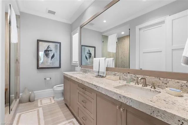 a bathroom with a granite countertop double vanity sink a toilet and a mirror