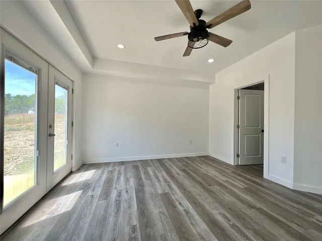 a view of empty room with wooden floor and fan