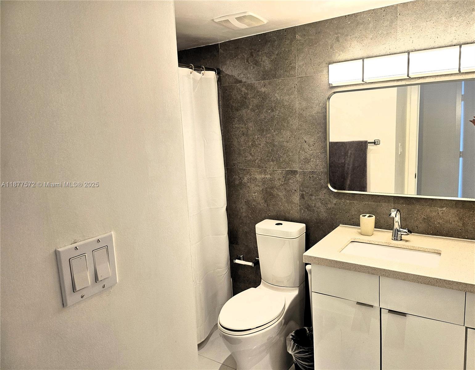 5161 Collins Avenue, Unit 707 Miami Beach, FL 33140 - Photo 17 of 69 a bathroom with a sink mirror vanity and toilet