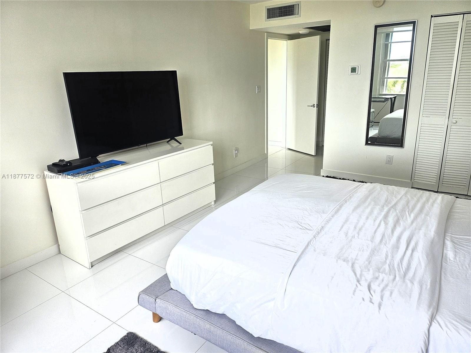 5161 Collins Avenue, Unit 707 Miami Beach, FL 33140 - Photo 23 of 69 a bedroom with a bed and flat screen tv