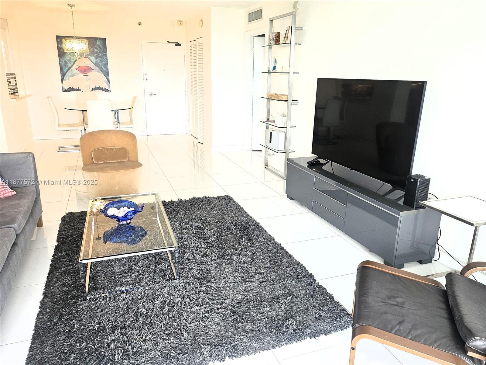 5161 Collins Avenue, Unit 707 Miami Beach, FL 33140 - Photo 4 of 69 a living room with furniture and a flat screen tv