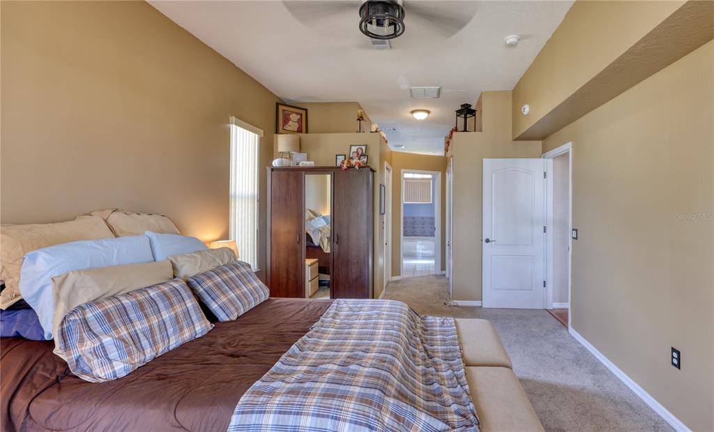 3473 Conifer Loop Spring Hill, FL 34609 - Photo 14 of 33 a bedroom with a large bed and a chandelier