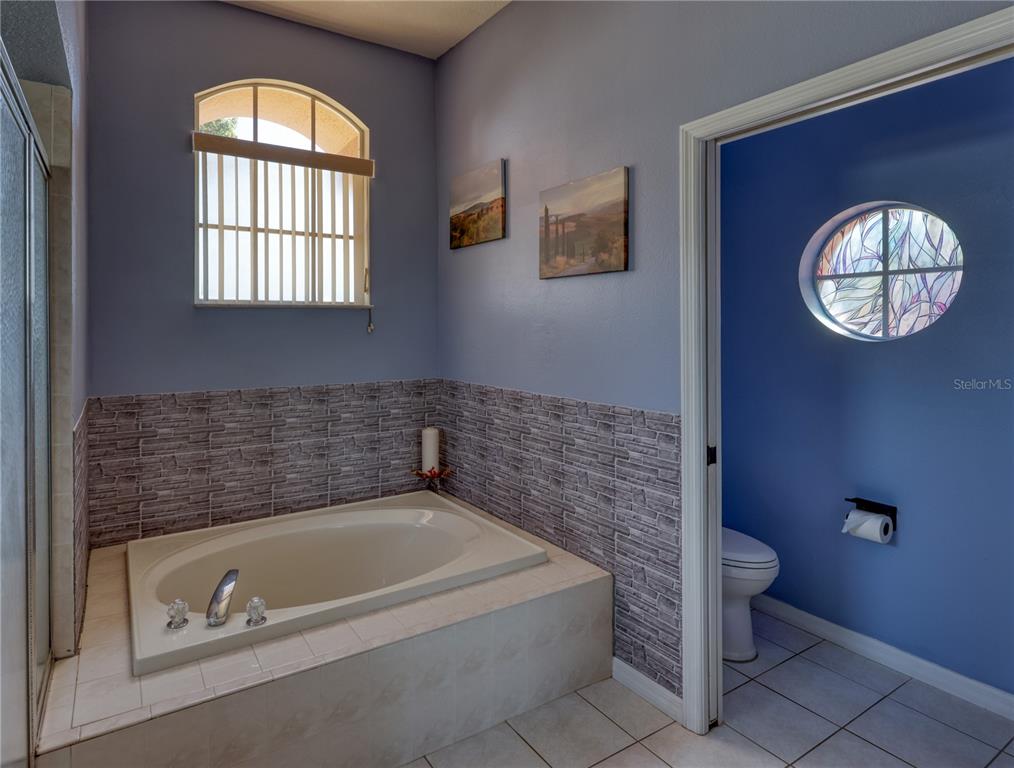 3473 Conifer Loop Spring Hill, FL 34609 - Photo 16 of 33 a bathroom with a tub a toilet and a window
