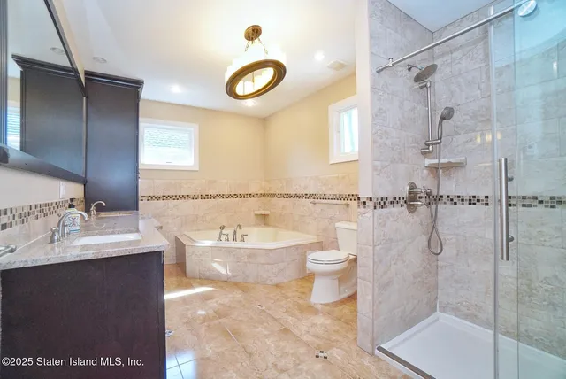 a bathroom with a granite countertop sink a toilet and shower