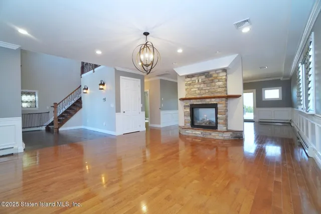 an empty room with wooden floor fireplace and windows