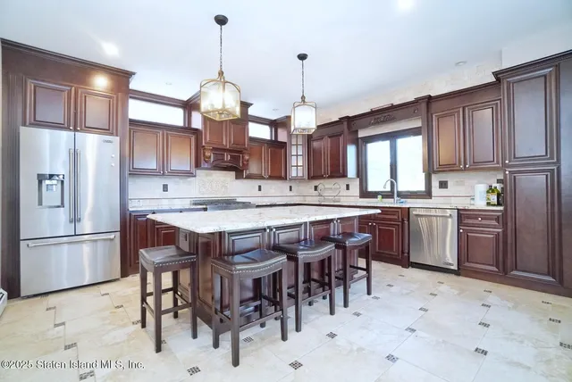 a kitchen with stainless steel appliances granite countertop a sink a stove a refrigerator cabinets a dining table and chairs