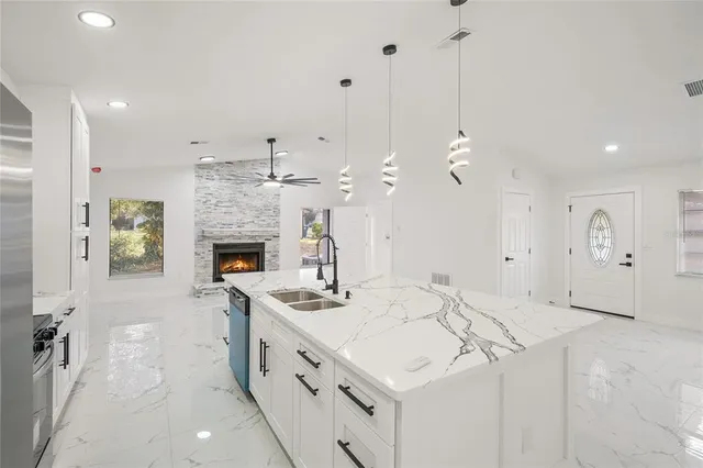 a kitchen with kitchen island a sink stainless steel appliances and a fireplace