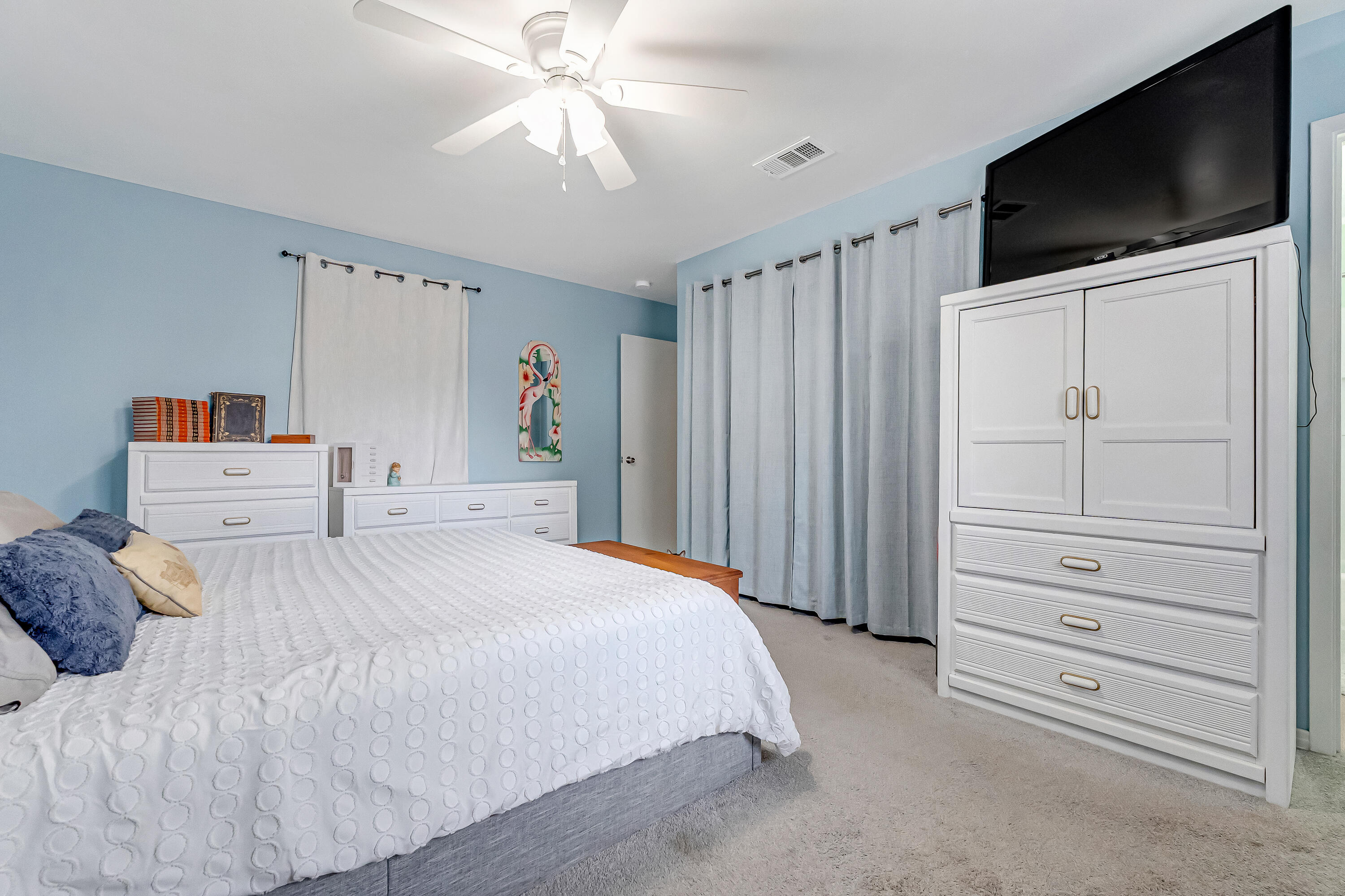 1811 Rattan Palm Drive Niceville, FL 32578 - Photo 31 of 57 a bedroom with a bed a flat screen tv and a chandelier