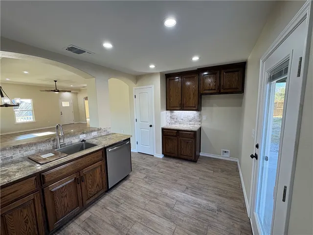 a large kitchen with stainless steel appliances granite countertop a large counter top a sink and a refrigerator