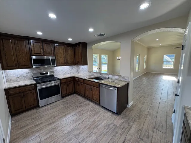 a large kitchen with stainless steel appliances and wooden cabinets