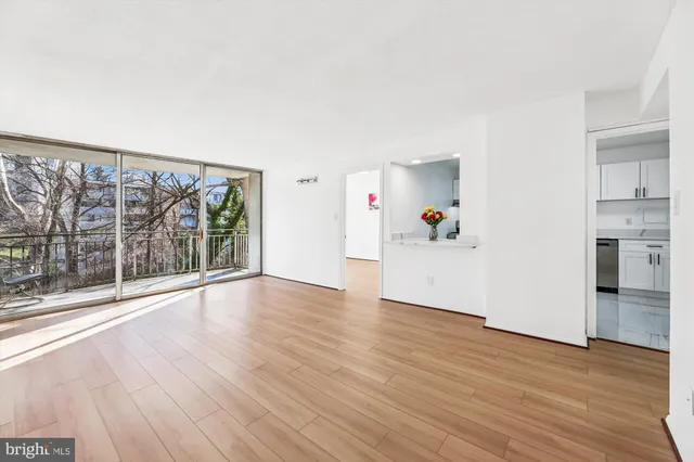 a view of an empty room with wooden floor and a window