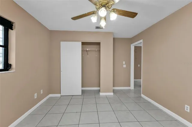 an empty room with closet and a chandelier fan