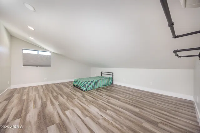a view of an empty room with wooden floor and a lamp