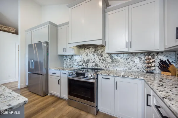 a kitchen with stainless steel appliances granite countertop a stove a refrigerator and a white cabinets