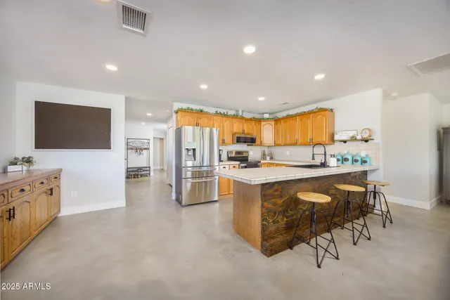 a kitchen with stainless steel appliances kitchen island granite countertop a refrigerator and cabinets