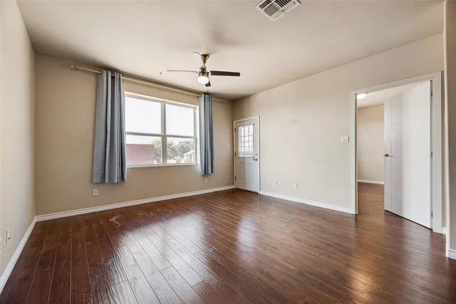 an empty room with wooden floor chandelier and windows