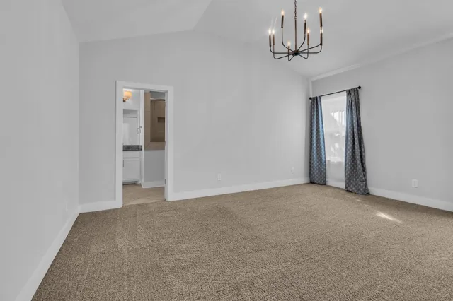 a view of an empty room with a chandelier fan