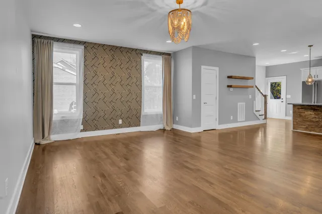 an empty room with wooden floor and stainless steel appliances