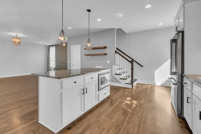 a kitchen with kitchen island granite countertop a stove a sink a refrigerator and a counter space