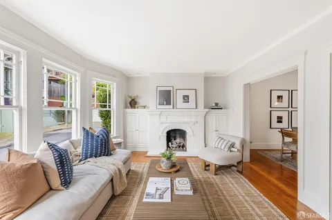 a living room with furniture a fireplace and large windows