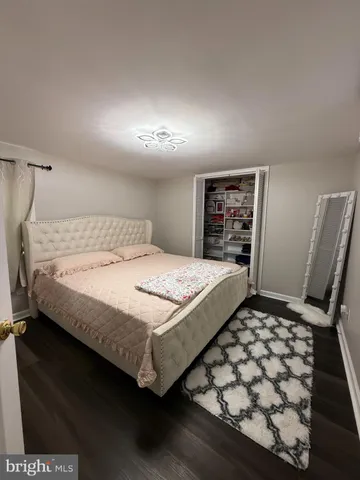 a bedroom with a bed and dresser with wooden floor