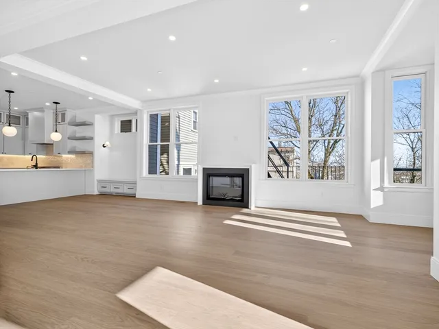 a view of an empty room with window and wooden floor