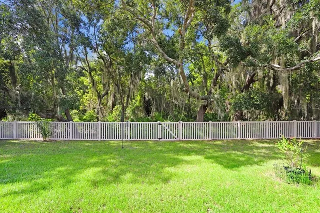 a view of a yard with grass and wooden fence