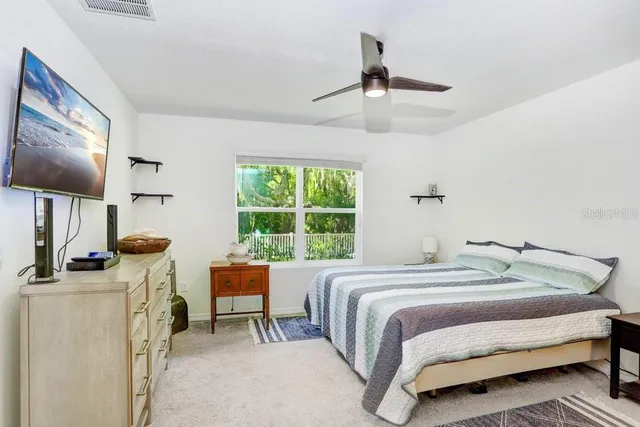 a bedroom with a bed and a flat tv screen on dresser