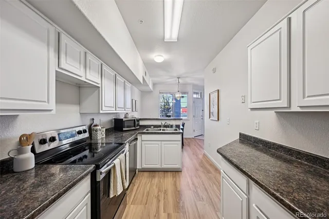 a kitchen with stainless steel appliances granite countertop a stove a sink dishwasher and cabinets with wooden floor