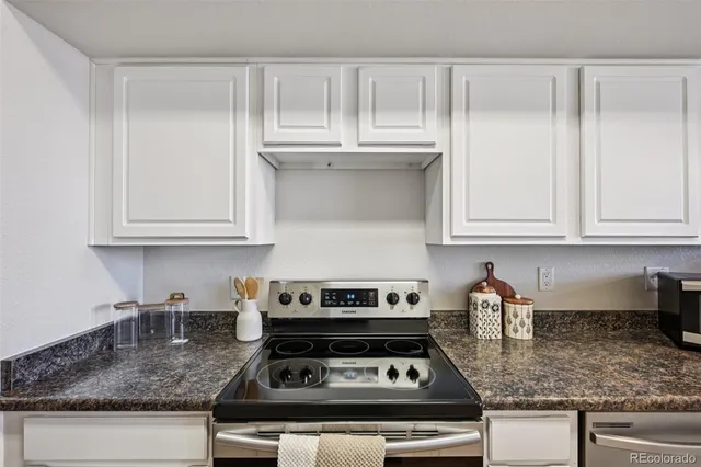 a kitchen with granite countertop white cabinets and a stove top oven