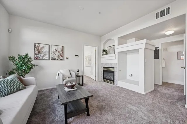 a living room with furniture a fireplace and a potted plant
