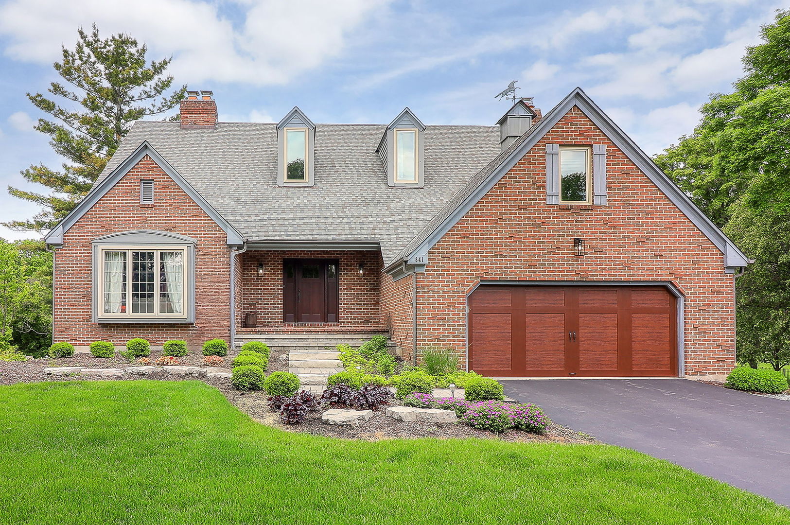 a front view of a house with a garden and plants