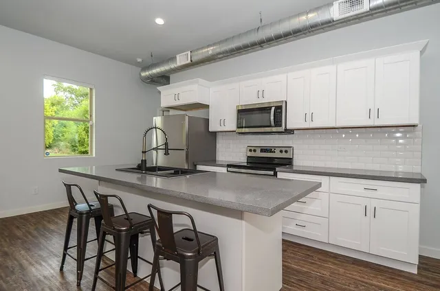 a kitchen with appliances a sink cabinets and wooden floor