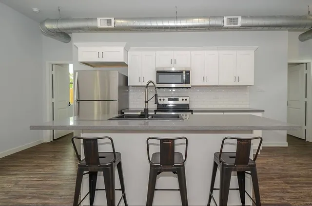 a kitchen with stainless steel appliances a white table and chairs in it
