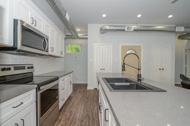 a kitchen with stainless steel appliances a sink stove and cabinets